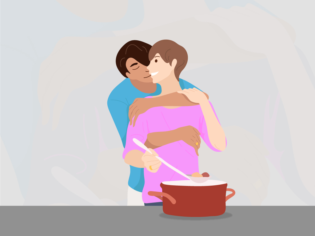 Woman in pink shirt cooking while man with blue shirt hugs her from behind.